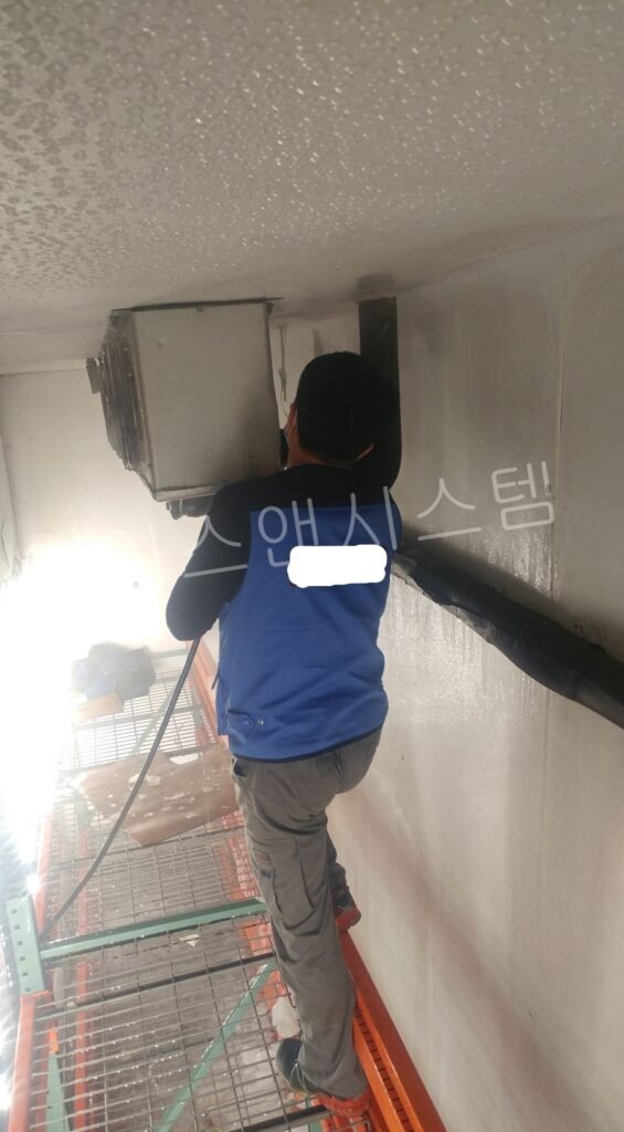 시흥 냉동창고 수리를 위해 사다리에 올라가 증발기 전기 회로와 제상 시스템을 정밀 점검하는 엔지니어