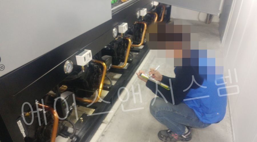 기계실 하단 콤프레샤 상태를 점검하고 체크리스트를 작성 중인 모습