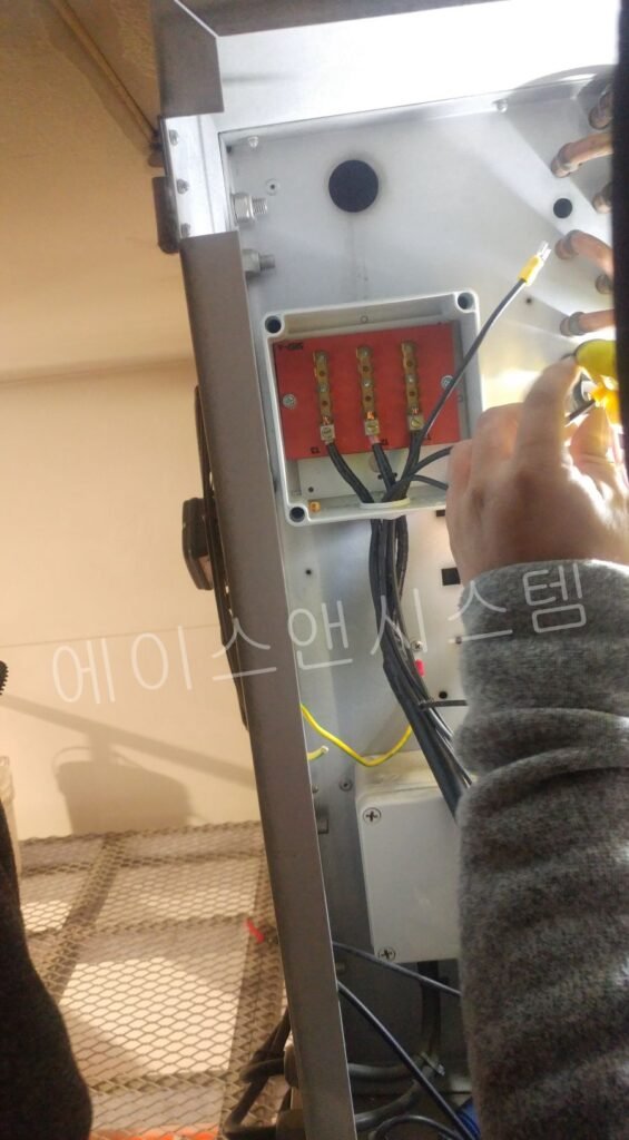 새롭게 교체된 단자대 보드에 정밀 압착된 전선들을 견고하게 볼트 체결하고 있는 엔지니어의 작업 모습