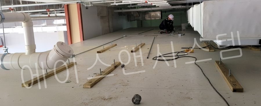 거대한 물류창고 천장을 가로지르는 대형 배관 설비. 냉방 효율을 극대화하기 위해 배관 외부에 두꺼운 고밀도 단열 보온재가 빈틈없이 시공된 모습